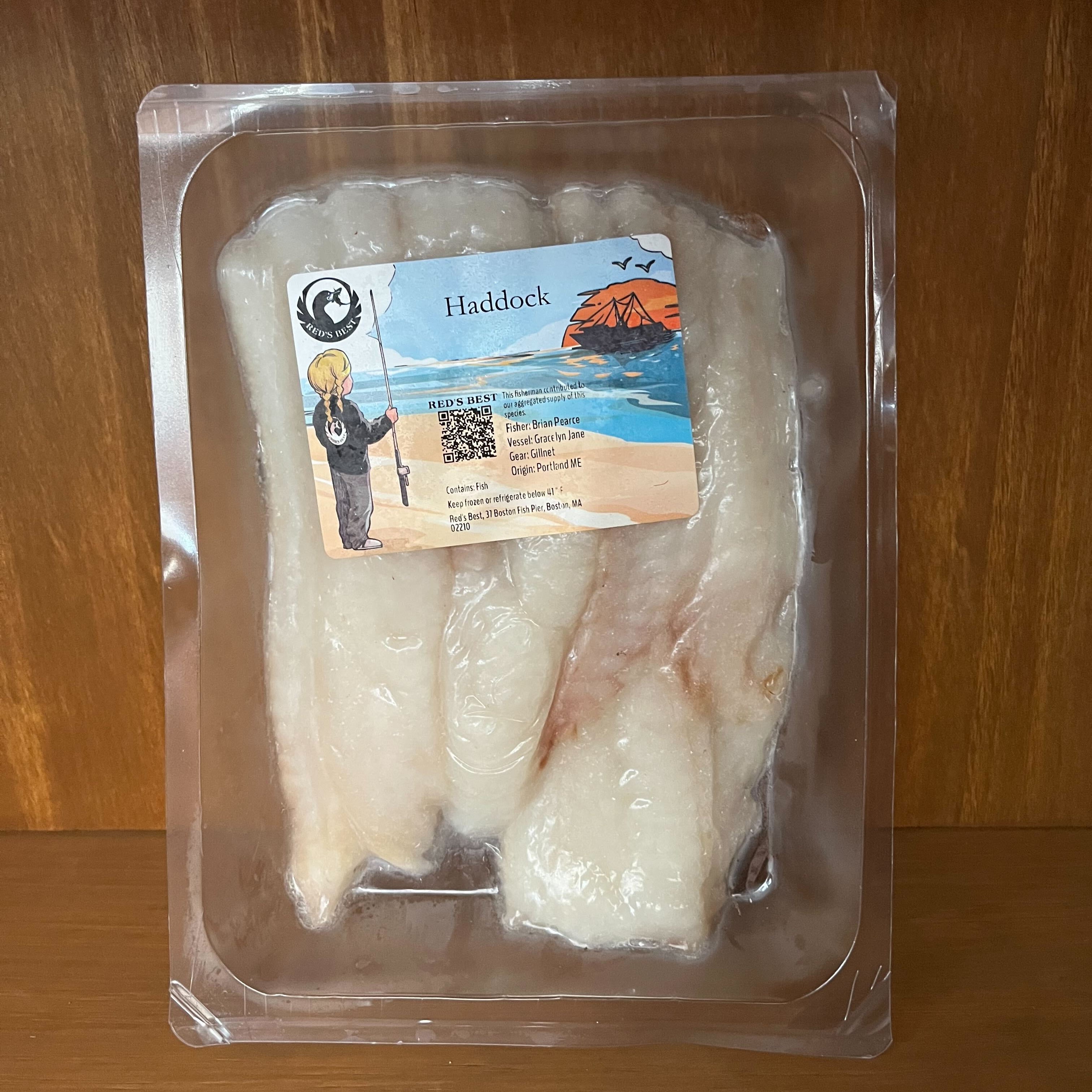 Packaged haddock fillets with a label on a wooden surface