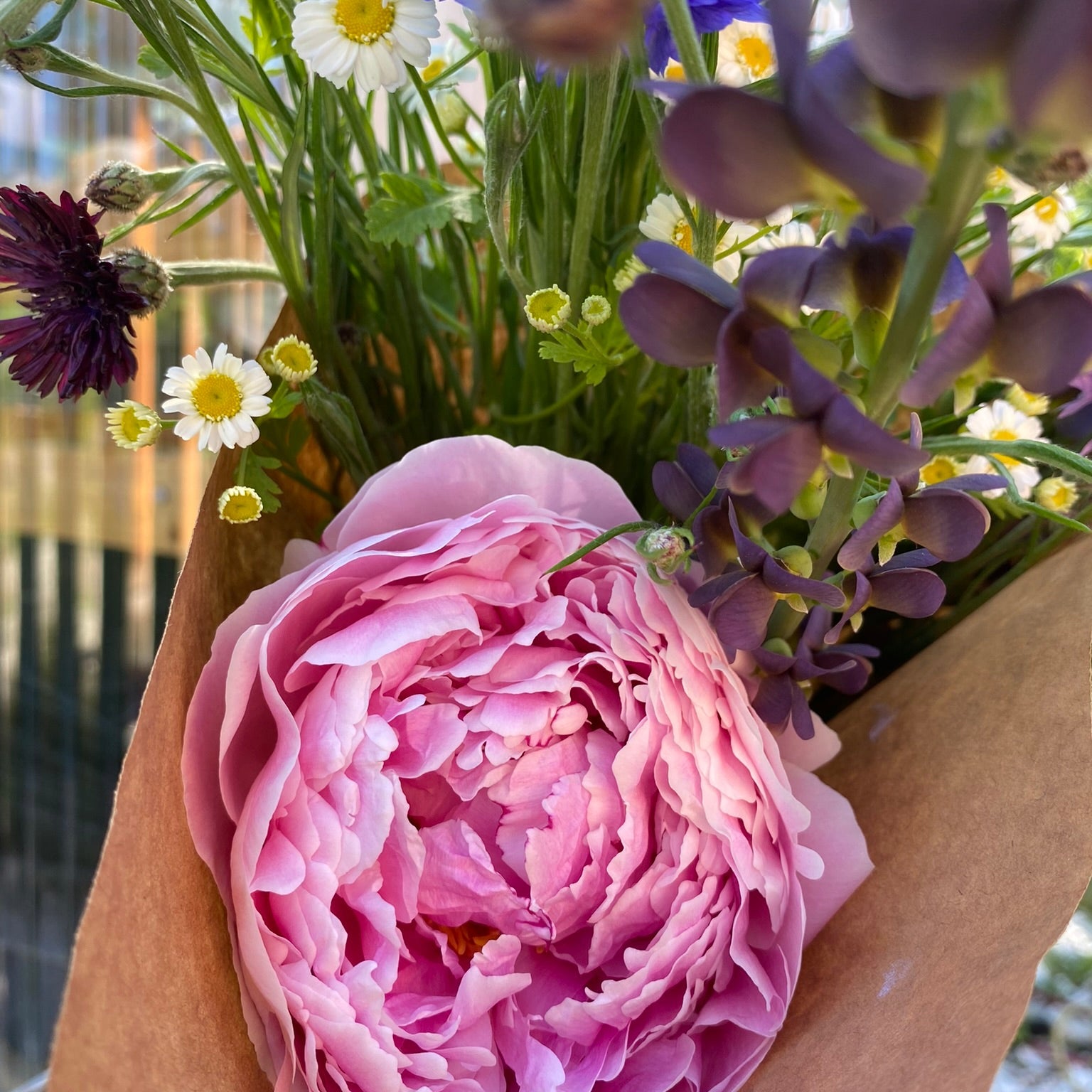 Bouquet of flowers with a pink rose held by a hand.